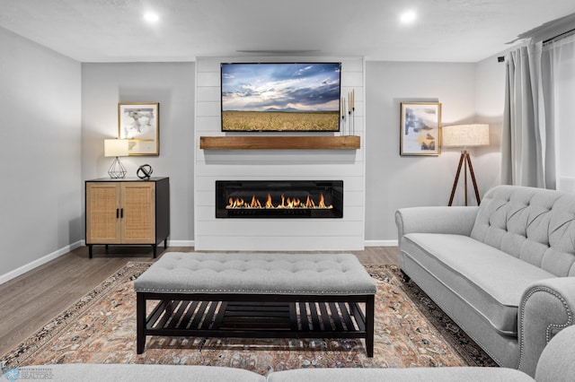 living area with recessed lighting, wood finished floors, baseboards, and a large fireplace