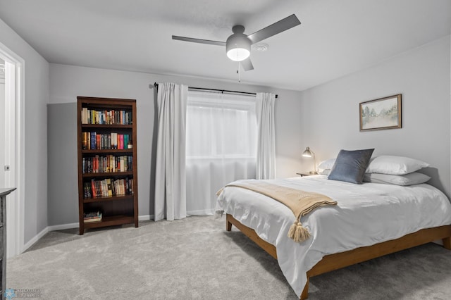 bedroom featuring light colored carpet, baseboards, and ceiling fan