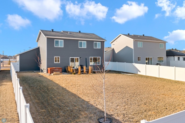 back of property with a fenced backyard and a hot tub