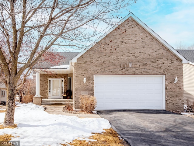 view of front facade with driveway, brick siding, roof with shingles, and an attached garage