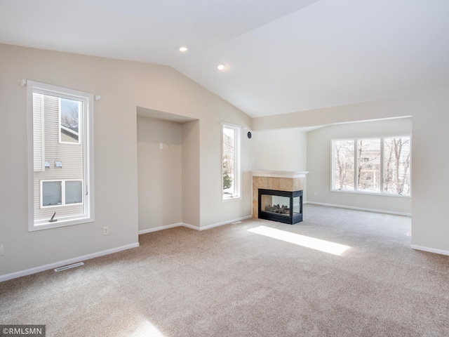 unfurnished living room featuring baseboards, carpet floors, lofted ceiling, recessed lighting, and a tile fireplace