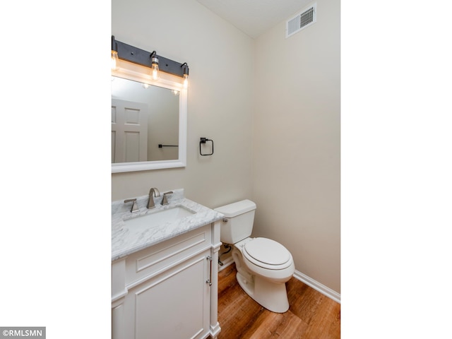 bathroom featuring visible vents, toilet, wood finished floors, baseboards, and vanity