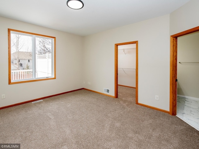 carpeted empty room featuring baseboards and visible vents