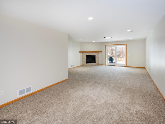 unfurnished living room featuring baseboards, visible vents, carpet floors, recessed lighting, and a tile fireplace