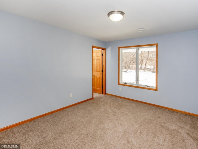 empty room featuring light carpet and baseboards