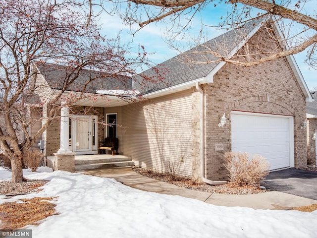 ranch-style home featuring an attached garage, brick siding, driveway, and a shingled roof