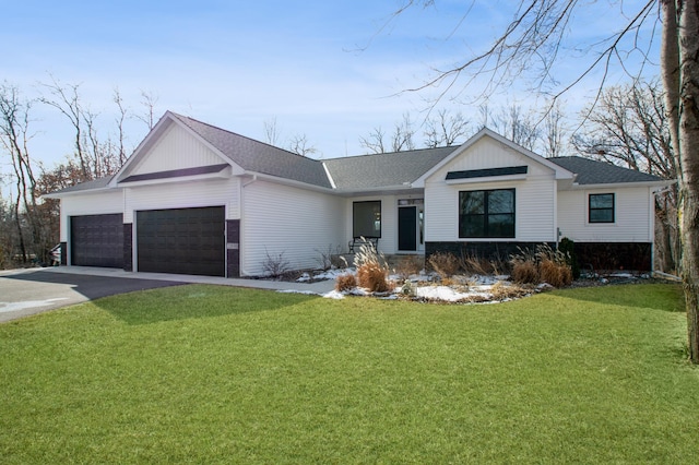 single story home with a garage, a shingled roof, a front yard, and aphalt driveway