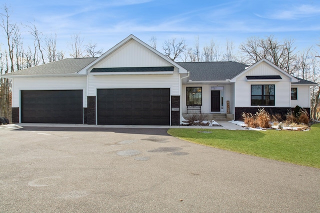 view of front of house with an attached garage, driveway, a front yard, and roof with shingles