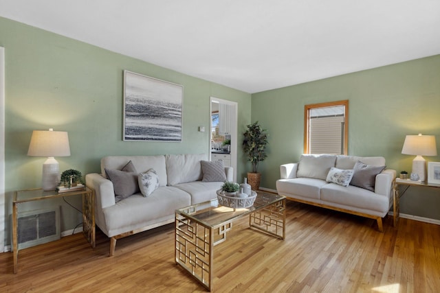 living room featuring visible vents, light wood-type flooring, and baseboards