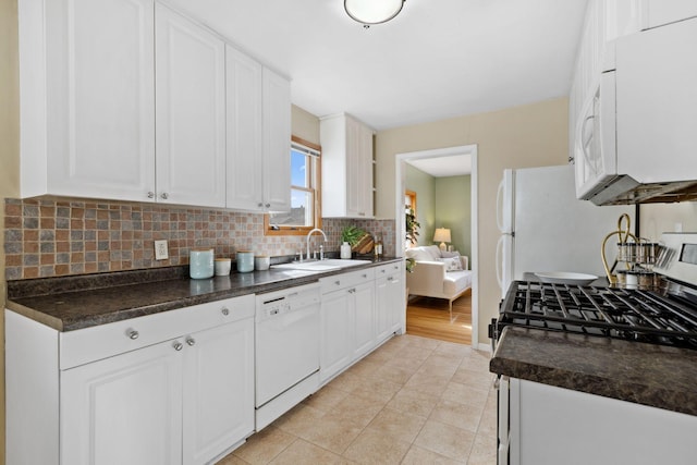 kitchen featuring a sink, backsplash, white appliances, and dark countertops