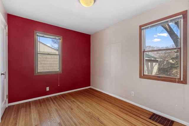 unfurnished room with light wood-style floors, plenty of natural light, baseboards, and visible vents