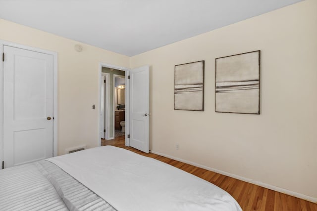 bedroom with wood finished floors, visible vents, and baseboards