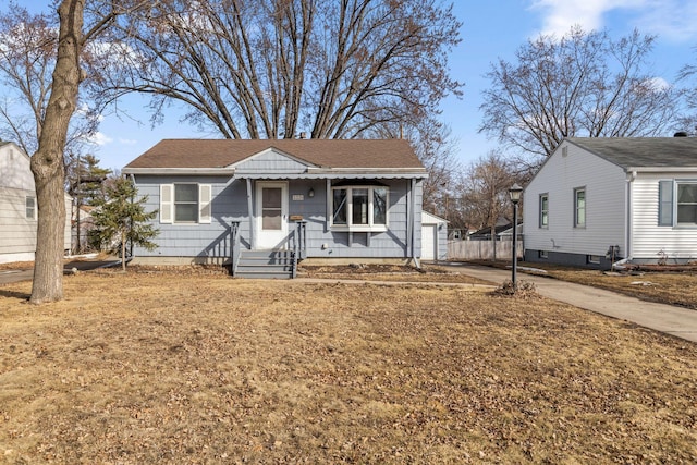 bungalow-style home with an outdoor structure, concrete driveway, and a shingled roof