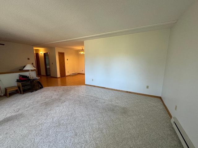 carpeted spare room with a baseboard heating unit, baseboards, baseboard heating, and a textured ceiling