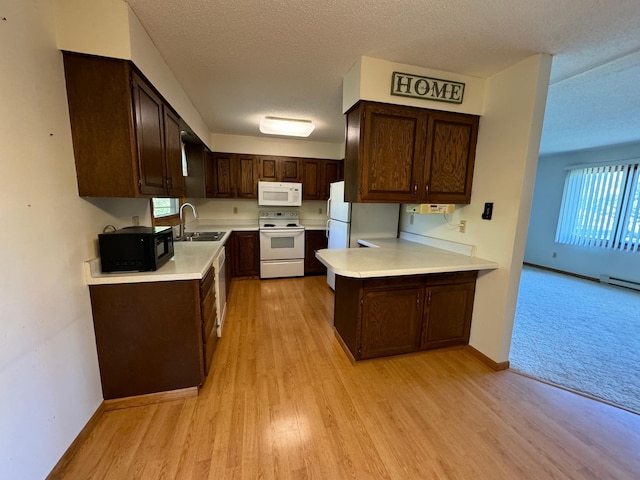 kitchen with a sink, white appliances, dark brown cabinets, and light countertops