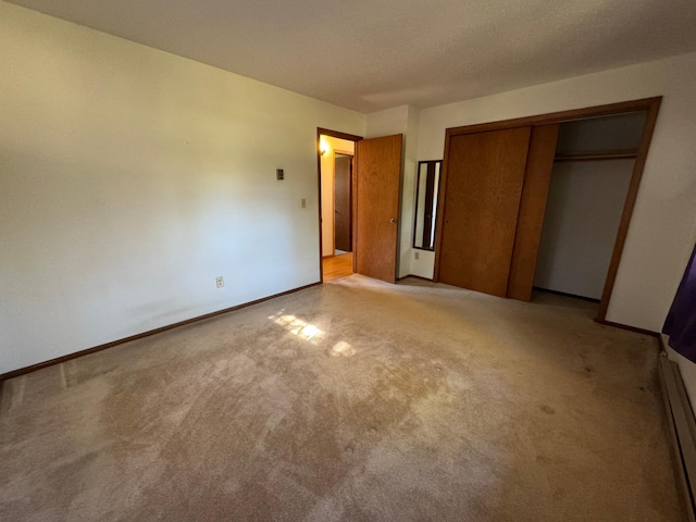 unfurnished bedroom featuring a closet, light colored carpet, and baseboards