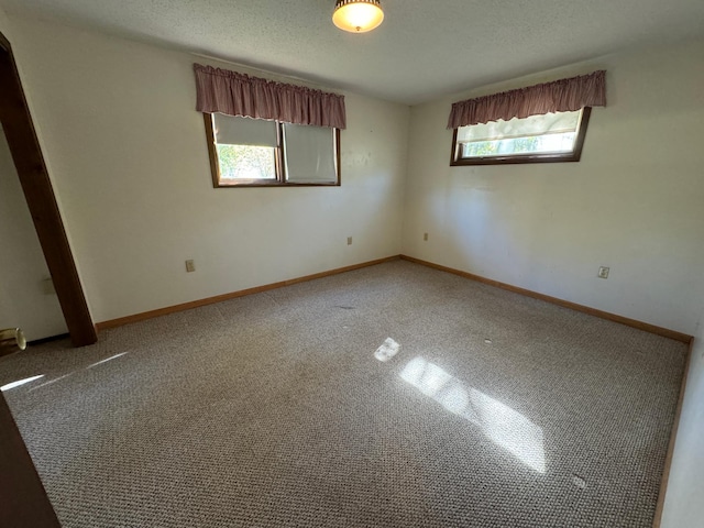 carpeted spare room with a textured ceiling and baseboards