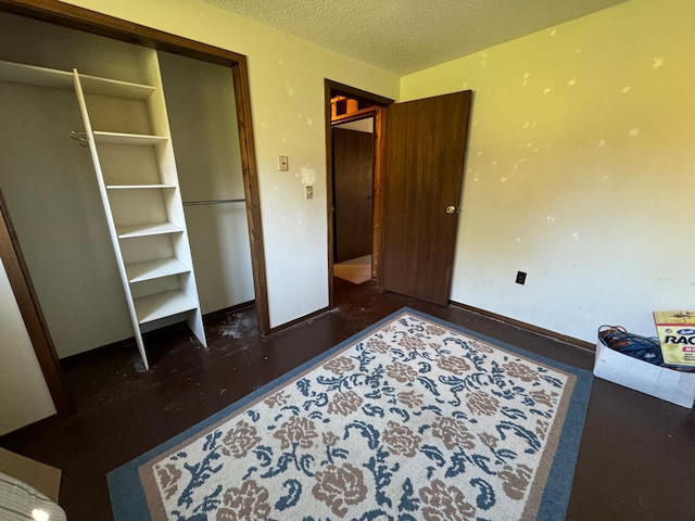 bedroom featuring baseboards, a textured ceiling, and wood finished floors