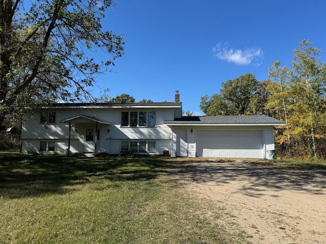 bi-level home with a garage, driveway, a chimney, and a front lawn