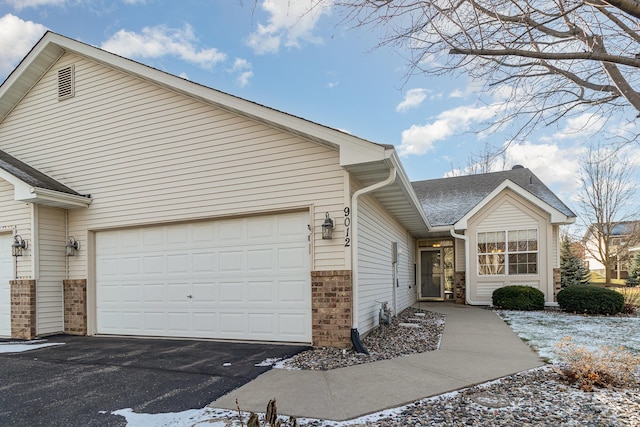 ranch-style house with a garage, brick siding, and aphalt driveway