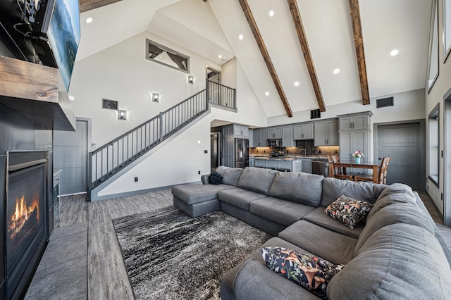 35647 Oxford Ave, Chisago Lake Twp, MN 55012 - living room featuring high vaulted ceiling, stairway, a tiled fireplace, recessed lighting, and beam ceiling