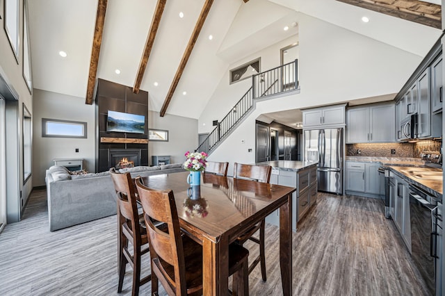 35647 Oxford Ave, Chisago Lake Twp, MN 55012 - dining space with high vaulted ceiling, a fireplace, stairs, wood finished floors, and beamed ceiling