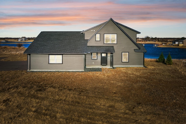 35647 Oxford Ave, Chisago Lake Twp, MN 55012 - back of house at dusk with a water view, roof with shingles, a yard, and a patio area