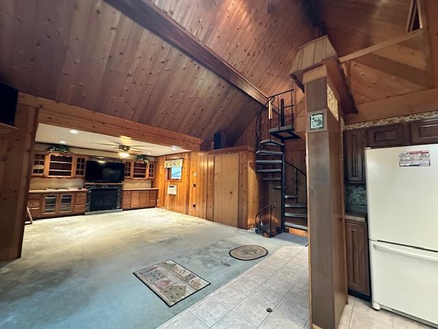 interior space with wooden walls, lofted ceiling with beams, ceiling fan, stairs, and wooden ceiling