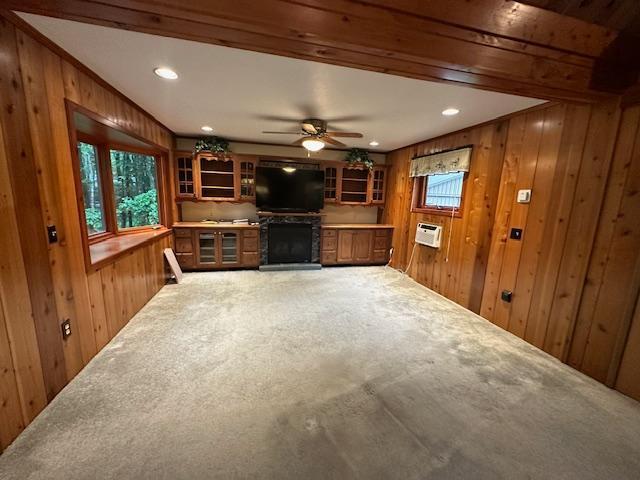 unfurnished living room with wooden walls, plenty of natural light, and carpet