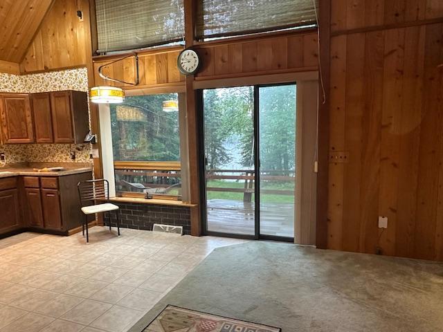 doorway with a wealth of natural light, wood walls, and high vaulted ceiling