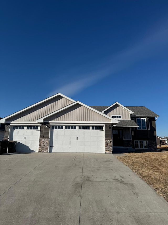 craftsman house featuring a garage, stone siding, and driveway