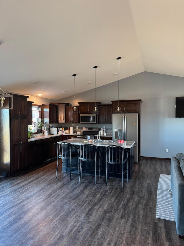 kitchen featuring a kitchen bar, dark wood-type flooring, appliances with stainless steel finishes, dark brown cabinets, and vaulted ceiling