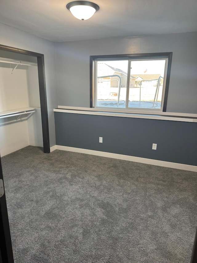 unfurnished bedroom featuring baseboards and dark carpet