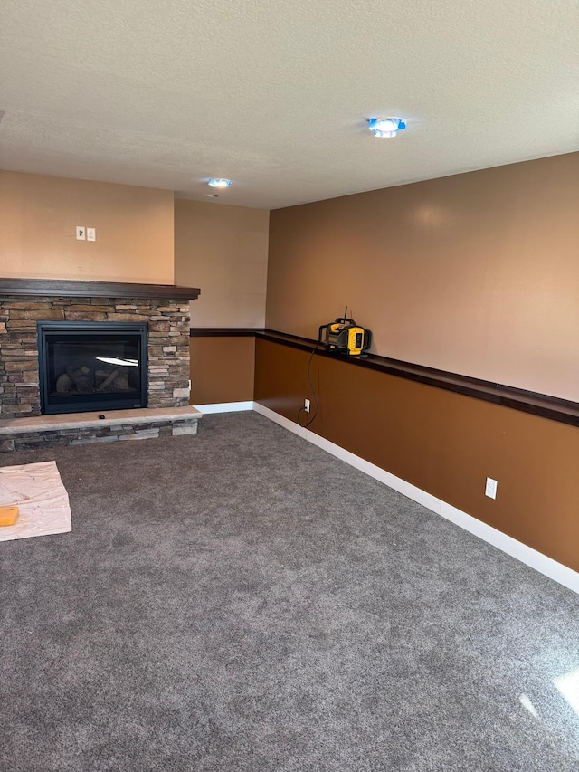 unfurnished living room featuring a fireplace, baseboards, carpet floors, and a textured ceiling