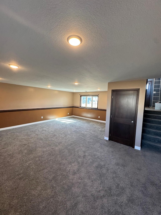 spare room featuring baseboards, carpet floors, and a textured ceiling