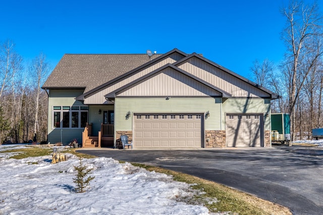 view of front of home featuring stone siding, driveway, roof with shingles, and an attached garage