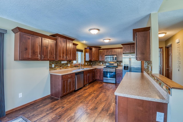 kitchen featuring dark wood-style flooring, a sink, light countertops, appliances with stainless steel finishes, and backsplash