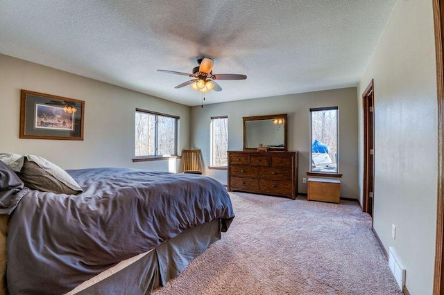 bedroom with a ceiling fan, visible vents, carpet floors, and a textured ceiling