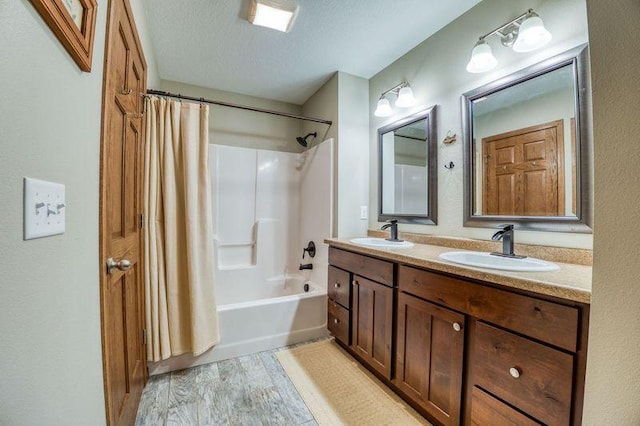 bathroom featuring a textured ceiling, double vanity, shower / tub combo, and a sink