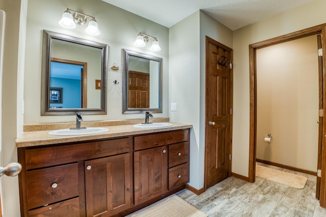 full bathroom featuring a sink, baseboards, and double vanity