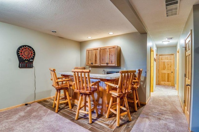 dining room featuring light carpet, baseboards, visible vents, and a textured ceiling