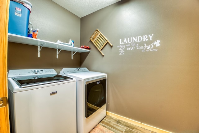 washroom with laundry area, washing machine and dryer, baseboards, and wood tiled floor