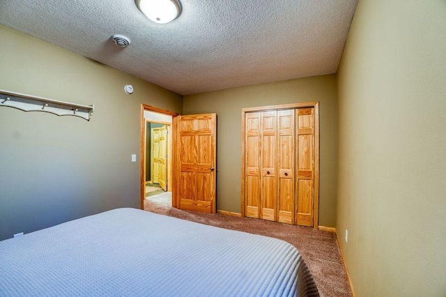 bedroom featuring a closet, baseboards, a textured ceiling, and carpet flooring