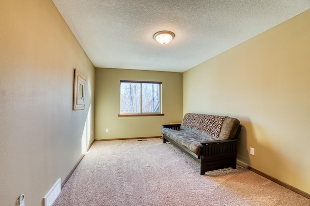 sitting room featuring baseboards, visible vents, carpet floors, and a textured ceiling