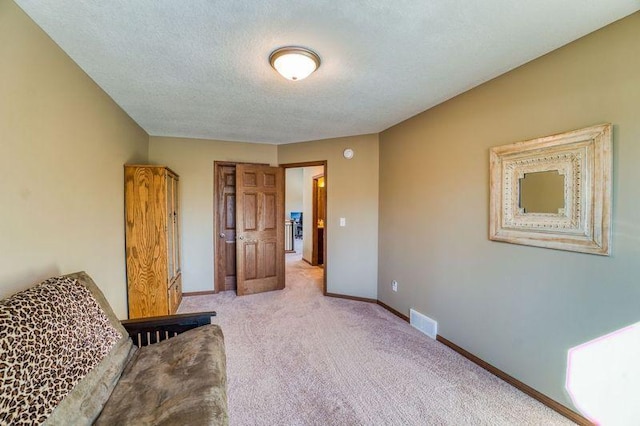 living area with visible vents, baseboards, light colored carpet, and a textured ceiling