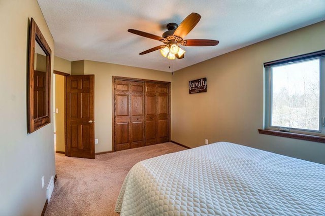 bedroom with baseboards, light carpet, a closet, a textured ceiling, and a ceiling fan