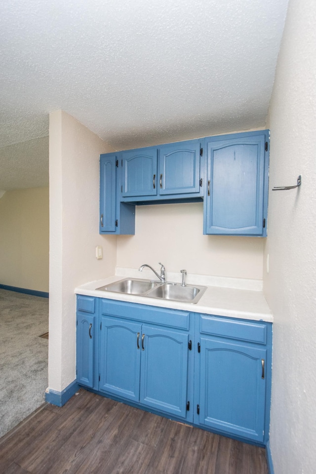 kitchen with dark wood-type flooring, blue cabinets, and a sink