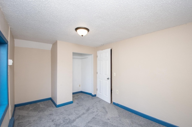 carpeted empty room featuring baseboards and a textured ceiling