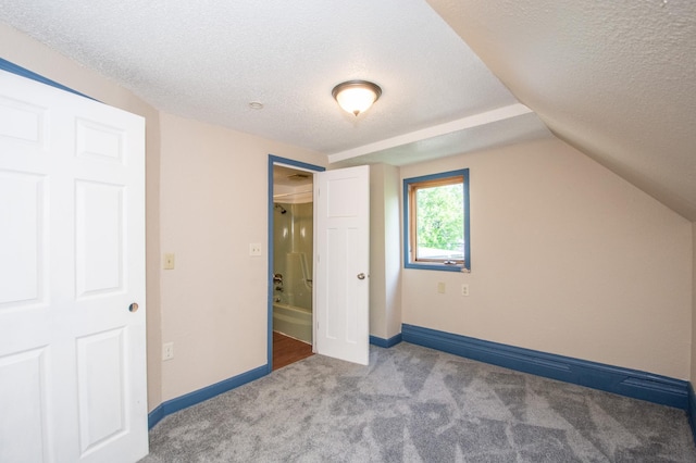 unfurnished bedroom featuring baseboards, a textured ceiling, carpet flooring, and vaulted ceiling