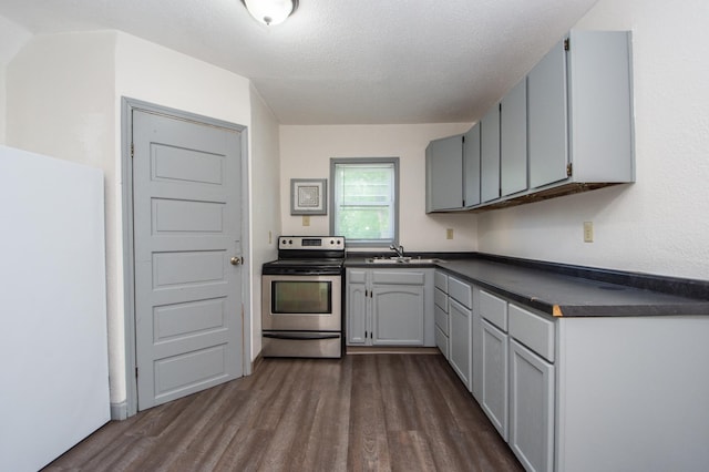 kitchen with a sink, dark countertops, stainless steel range with electric stovetop, and dark wood-style flooring